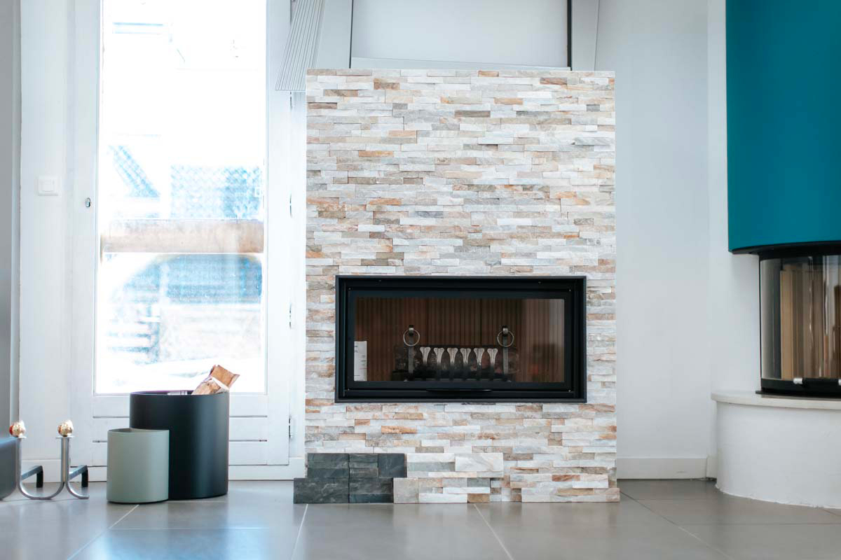 Cheminée moderne avec pierres naturelles et bois de chauffage à côté